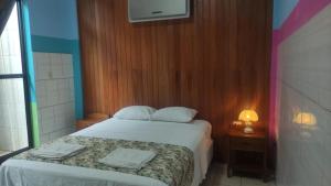 a small bedroom with a bed and a night stand with a lamp at HOSTAL AKEMI in Yurimaguas