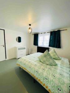 Schlafzimmer mit einem Bett mit grüner Bettwäsche und einem Fenster in der Unterkunft Apartment Secret room Paris-Stade de France in Aubervilliers