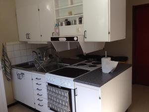 a kitchen with a stove and a sink and white cabinets at Hässleholmsgårdens Vandrarhem in Hässleholm