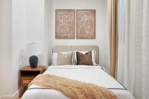 a bedroom with a white bed with a furry blanket on it at 1290-8 New Renovated 2 Bedrooms in UES in New York