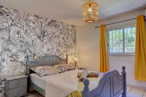 Schlafzimmer mit einem Bett mit Wandbild in der Unterkunft Bec Rose - Clim - Wi-fi - Jardin in Saint-Leu