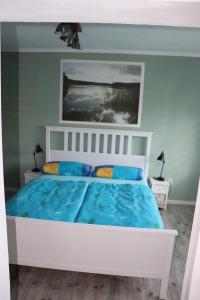 - une chambre avec un lit blanc et des draps bleus dans l'établissement Ferienwohnung Am See 55, à Bad Saarow