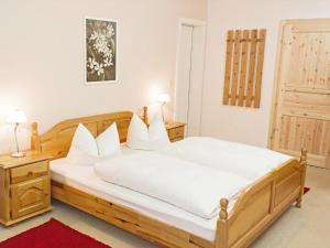 a bedroom with a wooden bed with white sheets at Berggasthof Lusen in Neuschönau