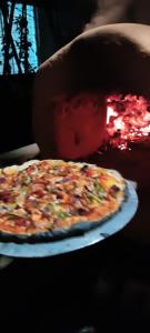 a person is holding a pizza on a table at Mansarover Home Stay in Kalimpong