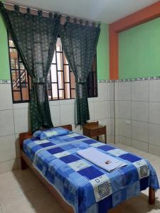 a bedroom with a bed with a blue comforter at HOSTAL AKEMI in Yurimaguas