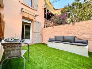 a small backyard with green grass and a couch at Petit Studio Charmant in Toulon