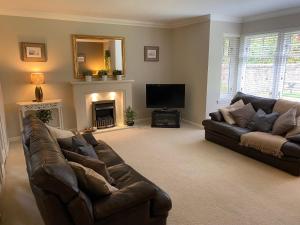 a living room with two leather couches and a television at Westwood Cottage in Aboyne