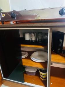 un estante con platos y una cafetera. en SR Apartments Milimani, Kisumu, en Kisumu