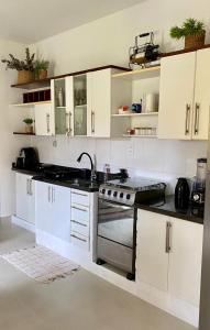 uma cozinha com armários brancos e um fogão em Bangalô Amarelo em Prado