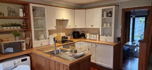 una cocina con armarios blancos y fregadero en Country Style, 2 bedroom house, Parking and superb location, en Norwich