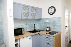 a kitchen with white cabinets and a clock on the wall at Ahoy Relax Apartmany Nesvady in Nesvady
