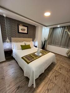 Un dormitorio con una cama grande y una mesa. en Otavalo Suites en Otavalo