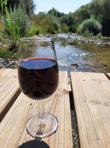 um copo de vinho sentado numa mesa ao lado de um rio em Bienvenue dans notre Gîte de Saint-Roch em Padern