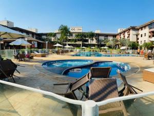 a swimming pool with chairs and tables and buildings at Life Resort - 2 quartos, 2 banheiros in Brasília