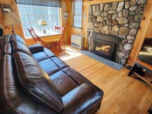 - un canapé en cuir dans le salon avec cheminée dans l'établissement Private Cabin on 1.7 acres w/ Fireplace White Mtns, à Intervale