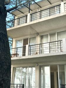 un grand bâtiment avec un balcon et un arbre dans l'établissement LIMANI, à Grigoleti