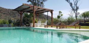 una piscina con sillas y un cenador en Casa Sierras de Córdoba Villa el Diquecito en La Calera