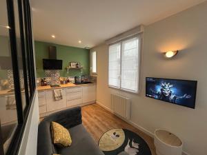 a living room with a couch and a tv on the wall at STUDIO OSAKA - HYPER CENTRE LORIENT in Lorient