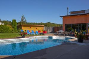 a swimming pool with chairs and a house at Complexe Hotelier Escoumins in Les Escoumins