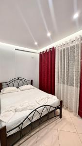 Schlafzimmer mit einem Bett und roten Vorhängen in der Unterkunft Tirana Apartment in Kashari