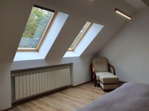 a attic bedroom with two windows and a bed and a chair at Apartament Piękny Widok in Bardo