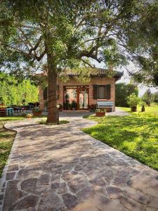 a stone walkway in front of a house with a tree at Agriturismo Fondo Novelle La Casina in Ferrara