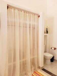 - un rideau de douche blanc dans la salle de bains pourvue de toilettes dans l'établissement NOVO Chalé Pôr do Sol Canoa Quebrada, à Aracati