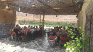 un grupo de personas sentadas en mesas en una habitación en MAISON D'HOTES IRIKI, en Tinerhir