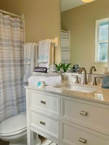 La salle de bains est pourvue d'un lavabo, de toilettes et d'un miroir. dans l'établissement WALK TO BEACH: 3BR home with spacious backyard, à Jacksonville Beach