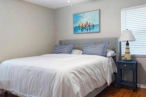 a bedroom with a bed with white sheets and blue pillows at WALK TO BEACH: 3BR home with spacious backyard in Jacksonville Beach