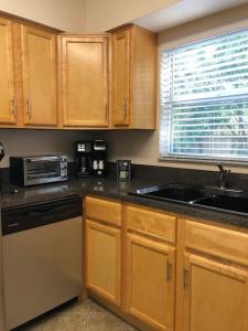 a kitchen with wooden cabinets and a sink and a microwave at WALK TO BEACH: 3BR home with spacious backyard in Jacksonville Beach
