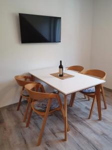 una mesa blanca y sillas con una botella de vino. en Apartmán U nás na Dolní Moravě, en Dolní Morava