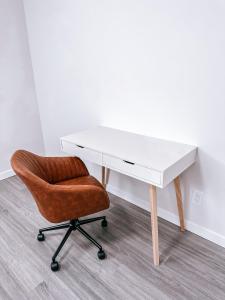 een wit bureau met een bruine stoel en een wit bureau bij Brand New 2 Bedroom Basement Suite in Calgary in Calgary