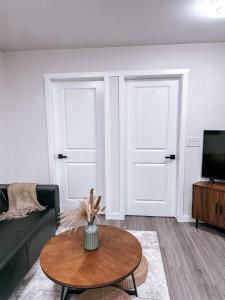 een woonkamer met 2 deuren en een tafel bij Brand New 2 Bedroom Basement Suite in Calgary in Calgary