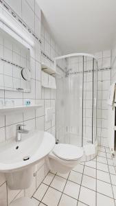 uma casa de banho branca com um chuveiro, um WC e um lavatório. em Vintage Hotel Petrisberg em Trier