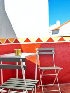 una mesa y una silla junto a una mesa y una pared roja en Old Évora Guest House en Évora