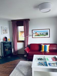 a living room with a red couch and a window at Steinbock - CharmingStay in Flumserberg