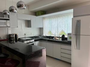 a kitchen with white cabinets and a black counter top at Mirante de Escarpas 1402 in Capitólio