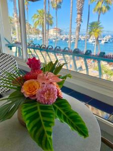 un jarrón de flores sobre una mesa con vistas a la playa en The Edgewater en Avalon