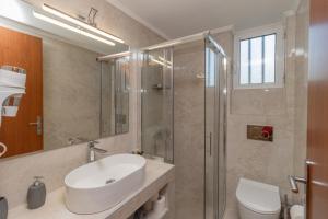 a bathroom with a sink and a shower and a toilet at Lagouvardos Beach Apartments in Marathopoli +54 photos