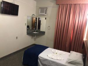um quarto de hotel com uma cama com uma flor em Avalon Executive em Goiânia