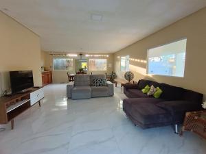 uma ampla sala de estar com sofás e uma televisão de ecrã plano em casa ampla com PISCINA e área verde em São José ao lado de Maragogi em São José da Coroa Grande