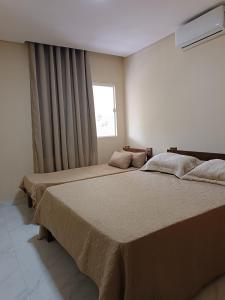2 camas en un dormitorio con ventana en casa ampla com PISCINA e área verde em São José ao lado de Maragogi, en São José da Coroa Grande
