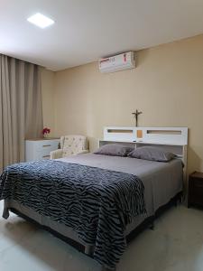 um quarto com uma cama com uma cruz na parede em casa ampla com PISCINA e área verde em São José ao lado de Maragogi em São José da Coroa Grande