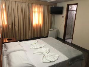 um quarto com uma cama com toalhas brancas em Avalon Executive em Goiânia