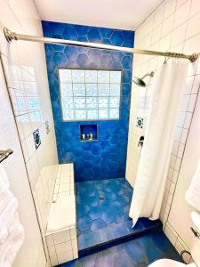 baño con ducha de azulejos azules y ventana en The Edgewater en Avalon