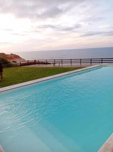 une piscine bleue avec l'océan en arrière-plan dans l'établissement Lyttos Bungalows, à Icapuí