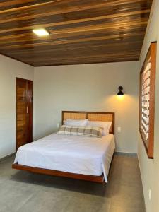 Lyttos Bungalows في إيكابوي: غرفة نوم بسرير كبير بسقف خشبي