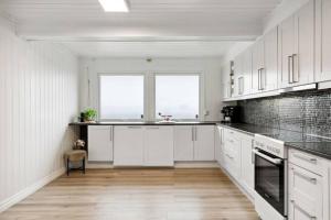 uma cozinha branca com armários brancos e uma grande janela em Stort hus sentralt 4 roms em Lillestrom