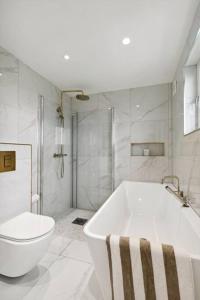 uma casa de banho branca com uma banheira e um WC em Stort hus sentralt 4 roms em Lillestrom